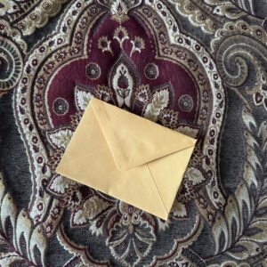 A letter in a golden envelope on an ornate rug.